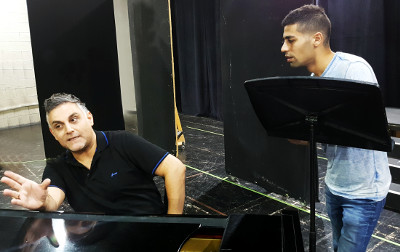 יוסף ארידן ותלמיד בזמן שיעור ליד פסנתר כנף בסטודיו לפיתוח קול
